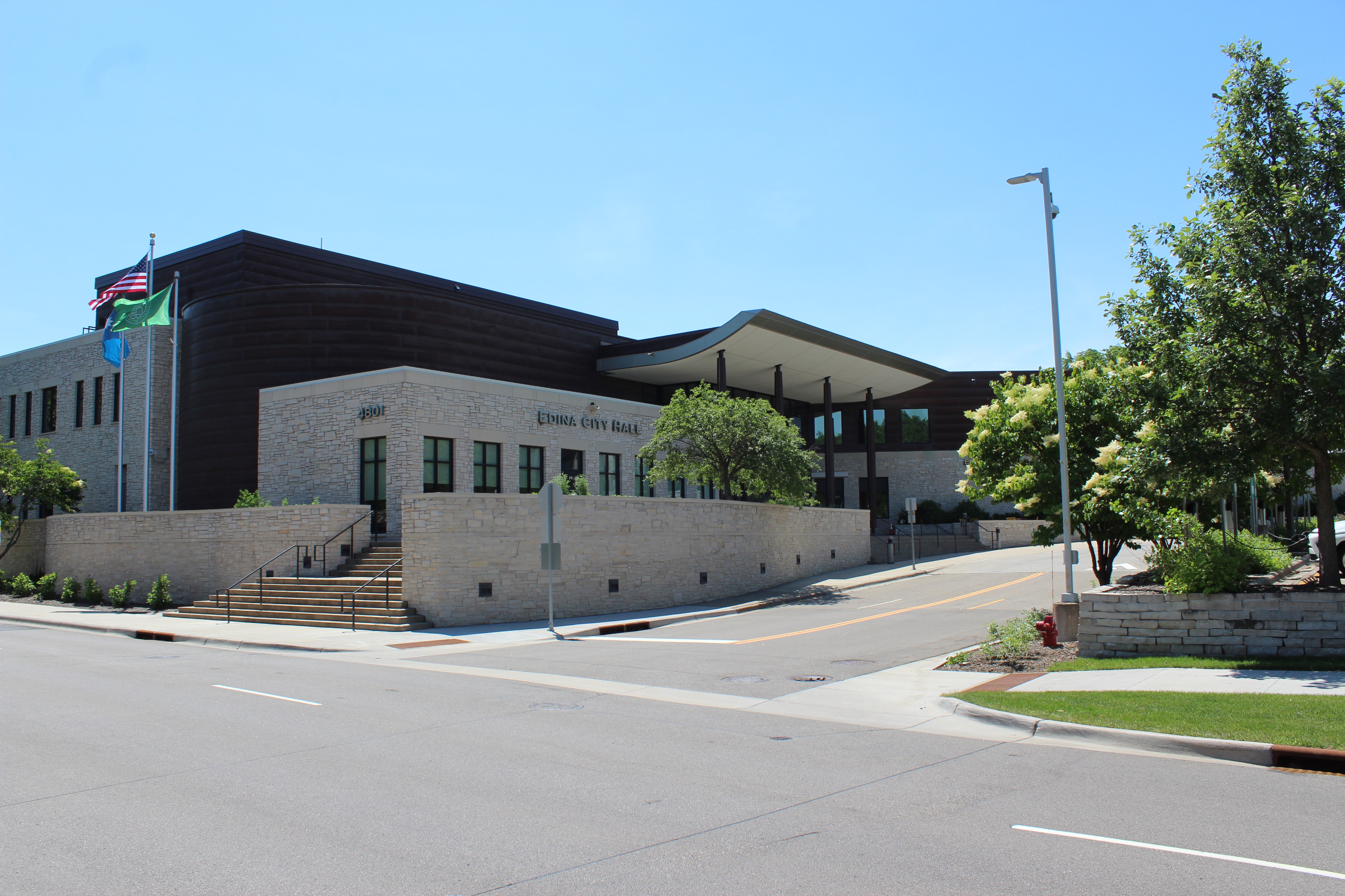 Stone and dark-clad Edina City Hall exterior above a landscaped street.