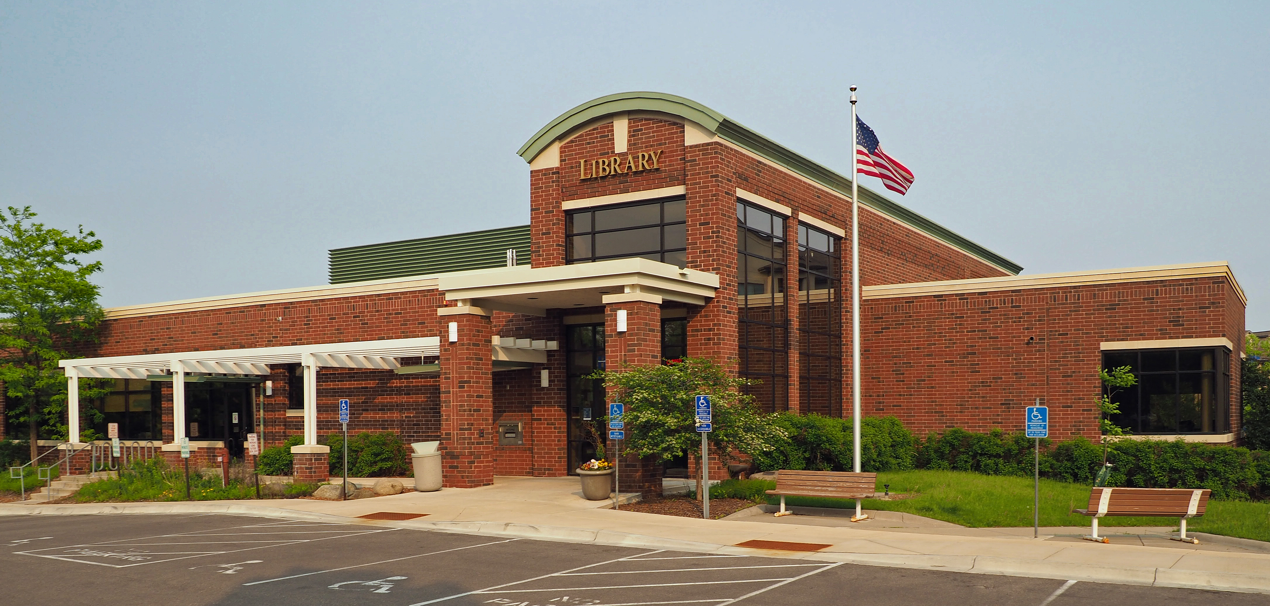 Brick Edina Library exterior with entrance canopy, benches and landscaping.